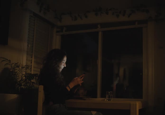 A woman sitting down video chatting on a smart phone