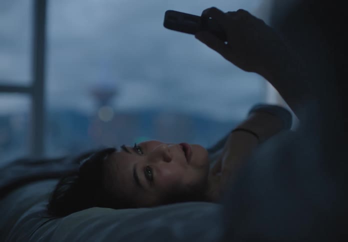 A woman laying down in bed video chatting on a smart phone