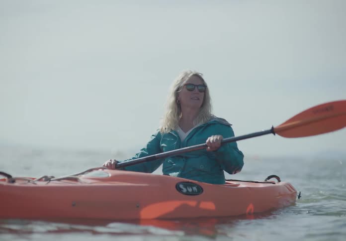 A woman with paddles kayaking in water