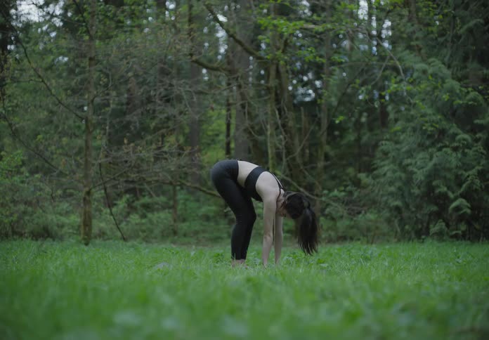 A woman is doing yoga by the forest