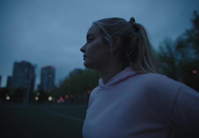 A white female teenager stands in a city park looking around