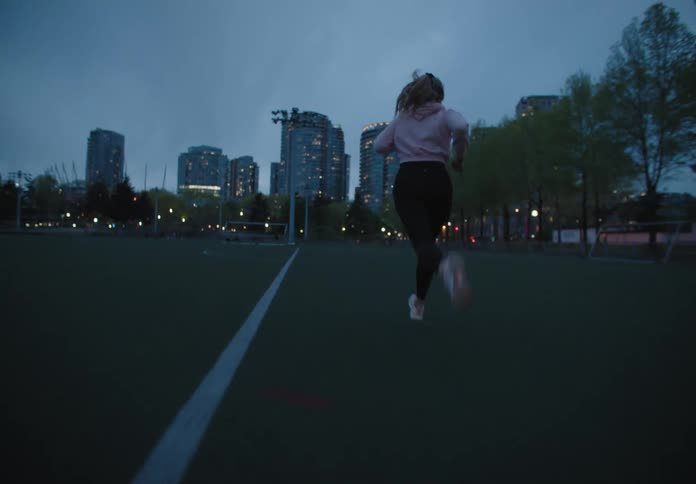 A woman running on a field with buildings in the foreground