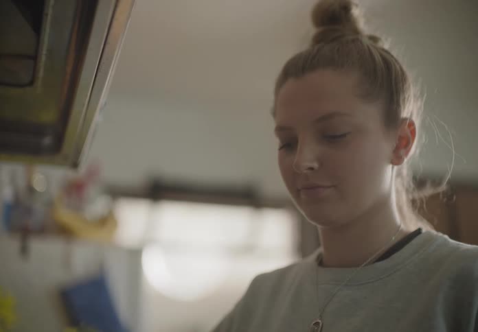 A woman in the kitchen frying eggs