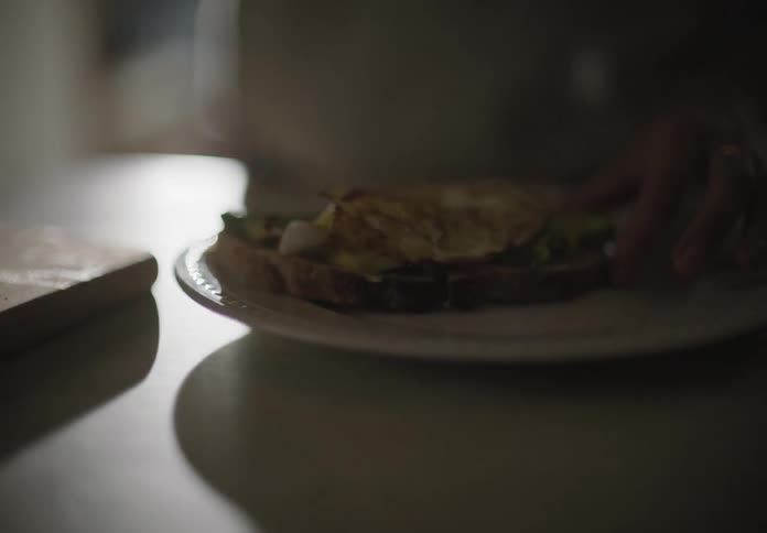 A person with a spatula placing eggs on a sandwich