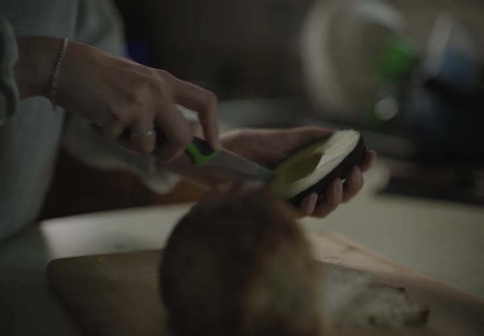 A woman with a knife cutting an avocado