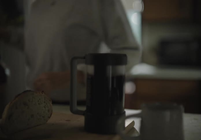 A white woman puts hot water into a large mug in a kitchen