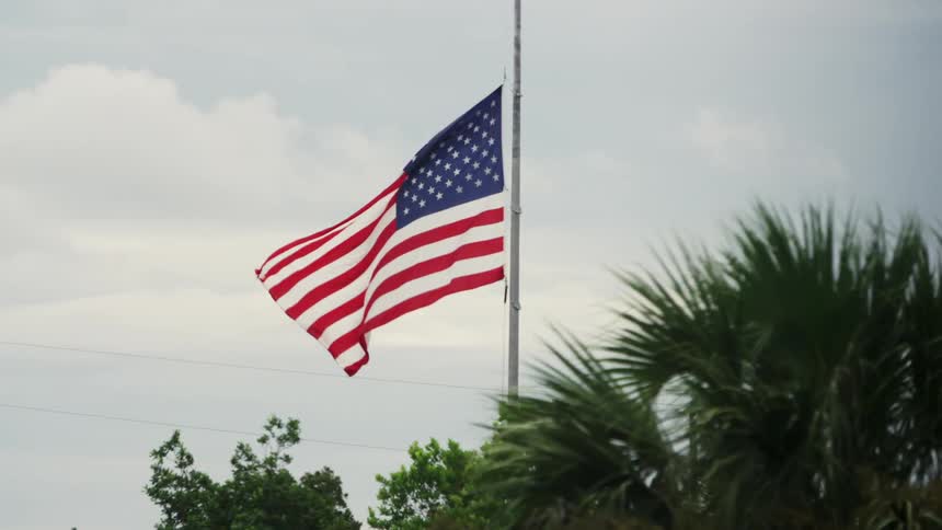 An american flag on a pole flies at half-mast