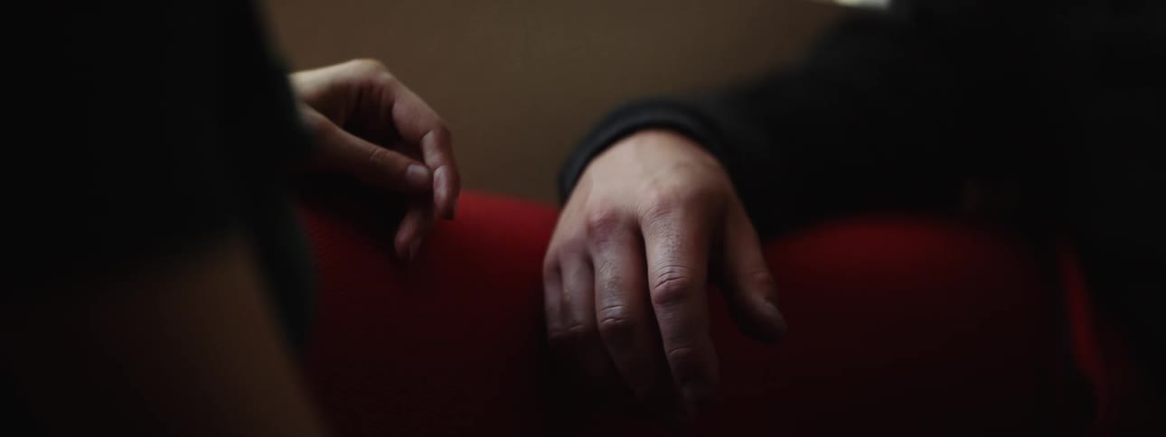 A man and woman sit and the woman squeezes the mans hand