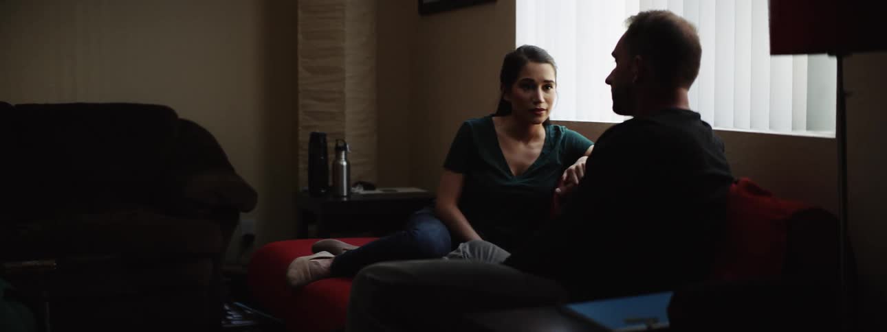 A man and a woman sit while reclining on a futon