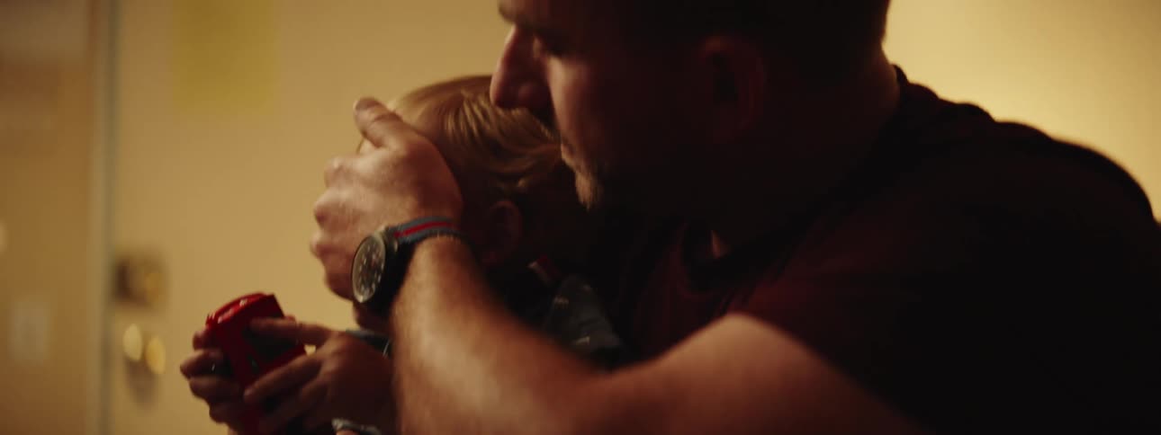 A father hugs his infant son while playing around with him