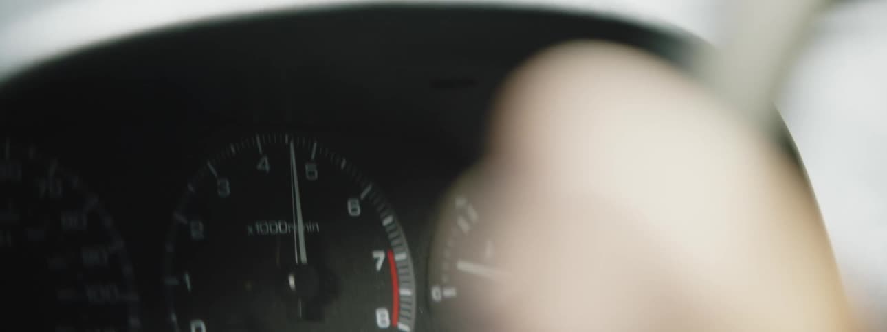 A person holding on to a steering wheel as the speedometer goes up and down