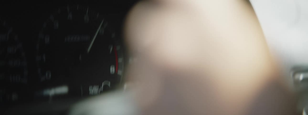 A person holding on to the steering wheel as their speedometer goes up and down