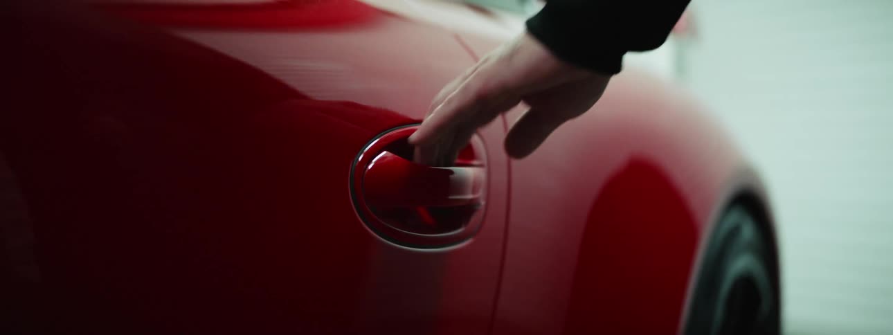 A white man grabs a cars door handle and pops the door open