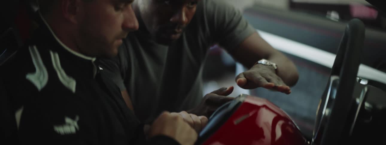 A black man speaks carefully to a white sports driver