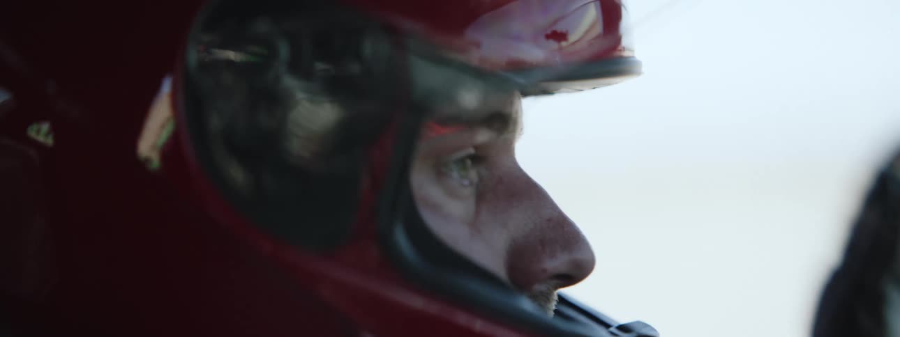 A white man looks concerned as he slaps down a helmets visor over his face