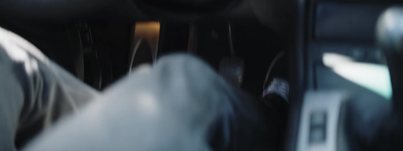 A person sitting in a car mashing the pedals with their foot