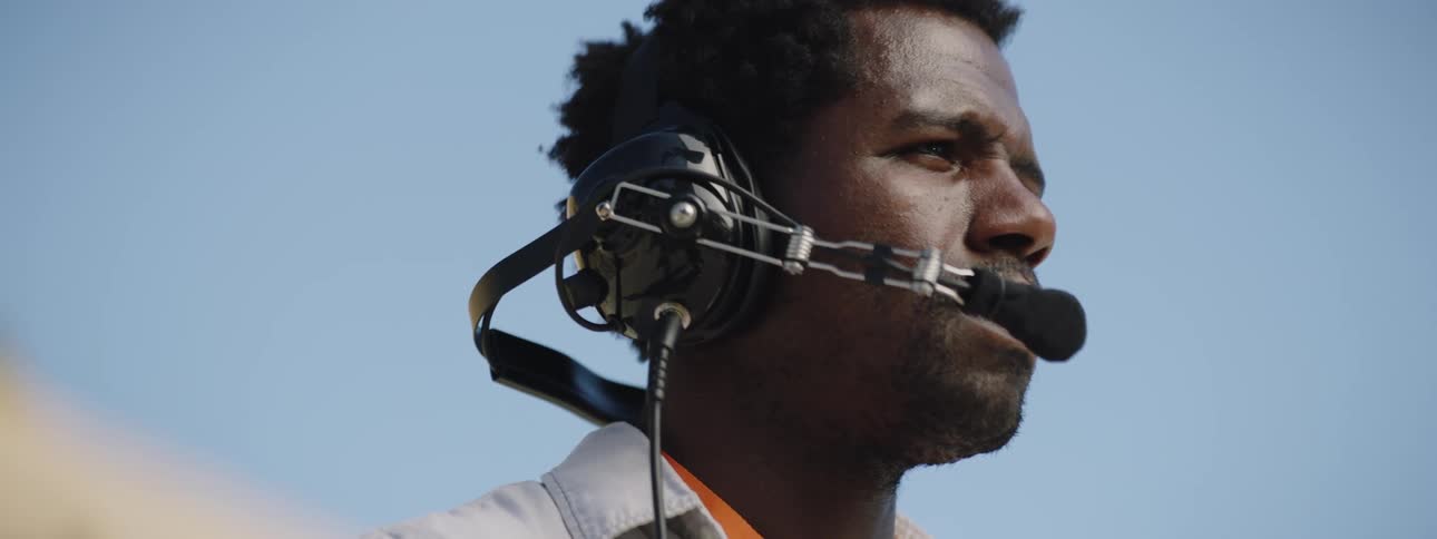 A man wearing a headset is standing outdoors