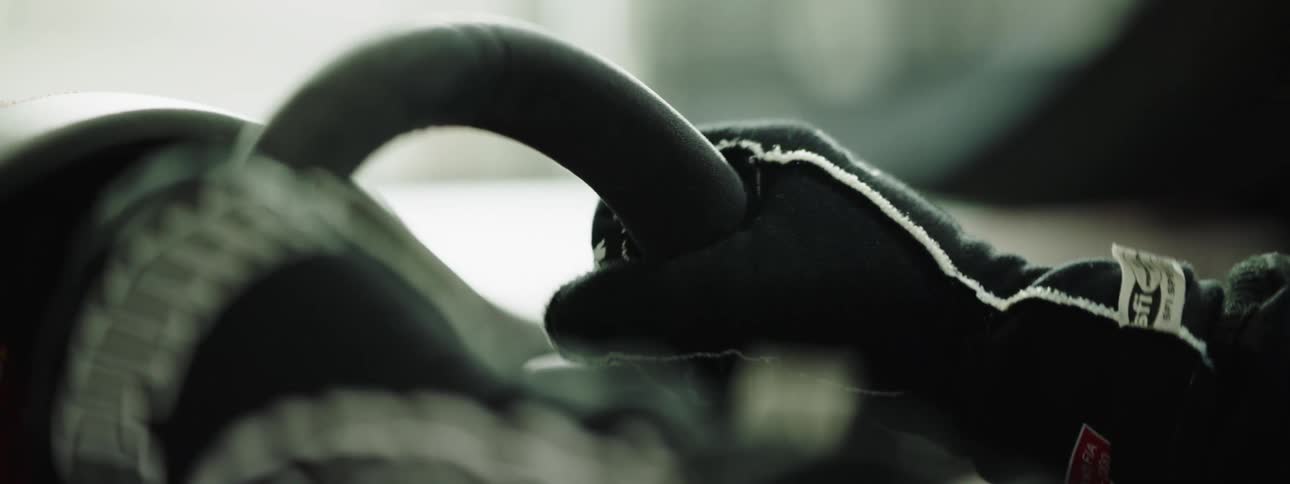 A driver wearing gloves grips the steering wheel