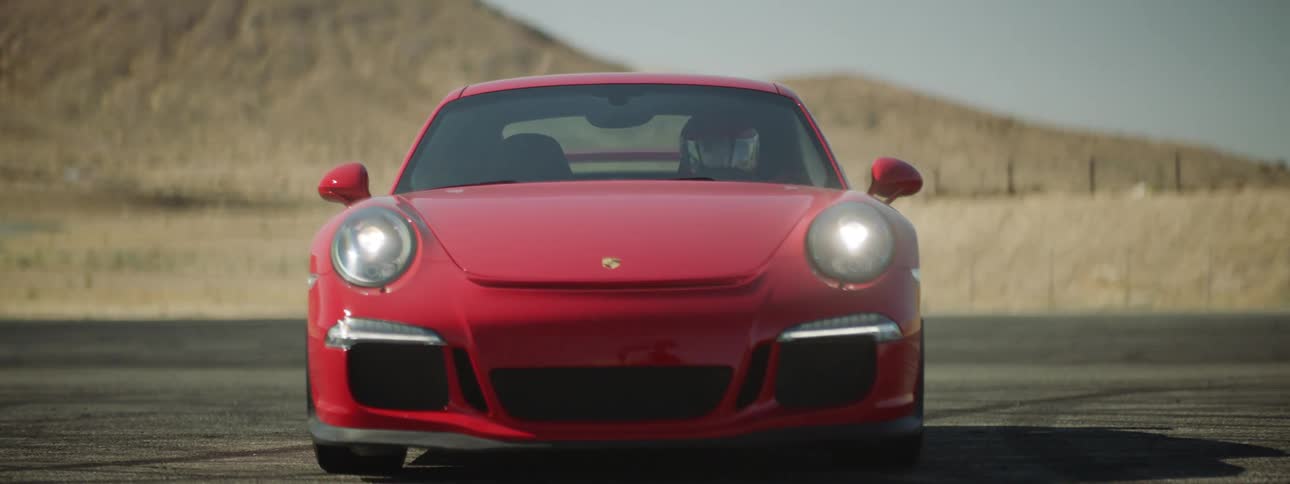 A red racing car sits on pavement out in the desert