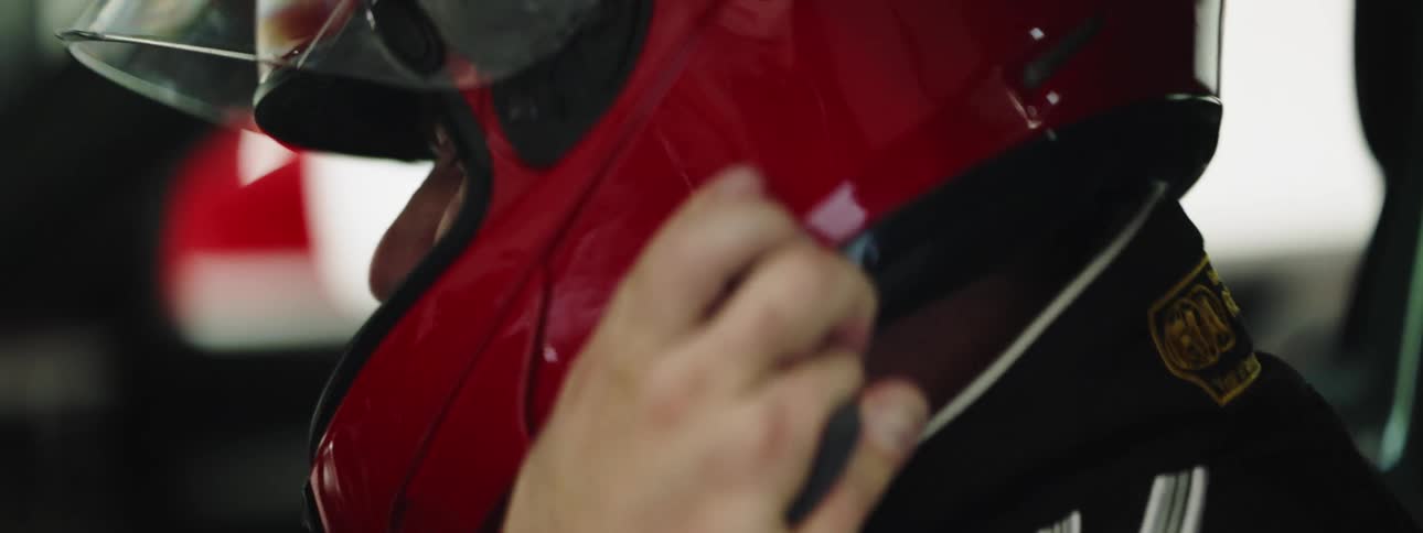 A race car driving putting on his racing helmet while sitting in his vehicle