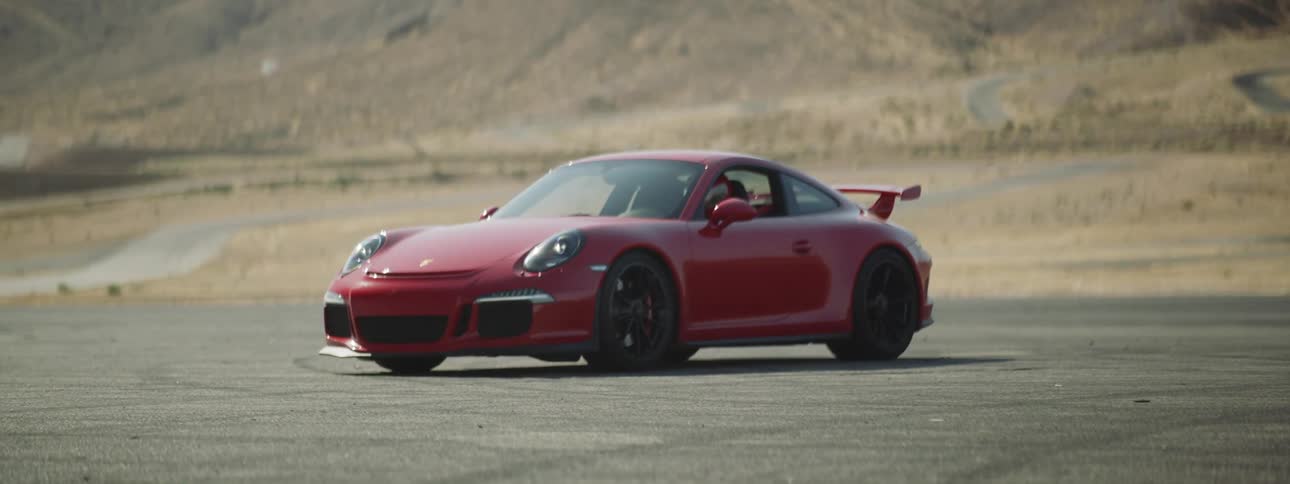 A red sports car sits on pavement out in the desert