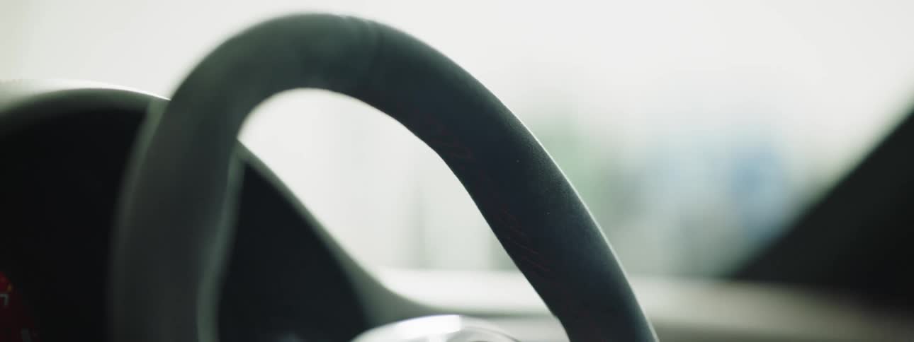A person with gloves grabbing on to a steering wheel