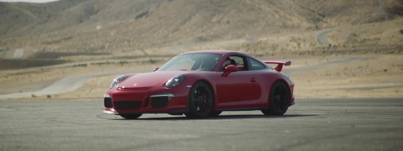 A red sports car sits on pavement in a desert