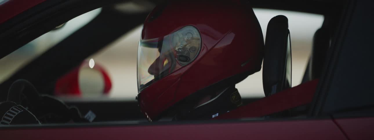 A man wearing a helmet is sitting in a car in a rural area