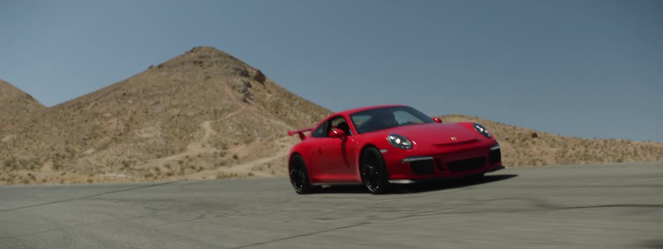 A red racing car tears down a racing track in the desert