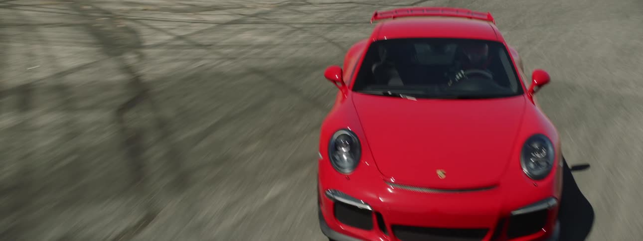 A red porsche races on an empty desert track on a sunny day