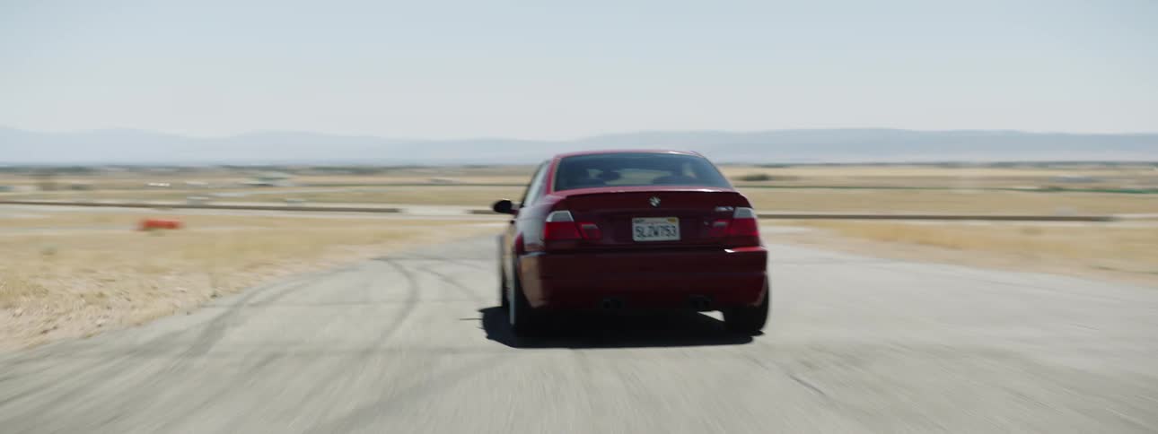 A person drives a racing car through a turn on a track out in the desert