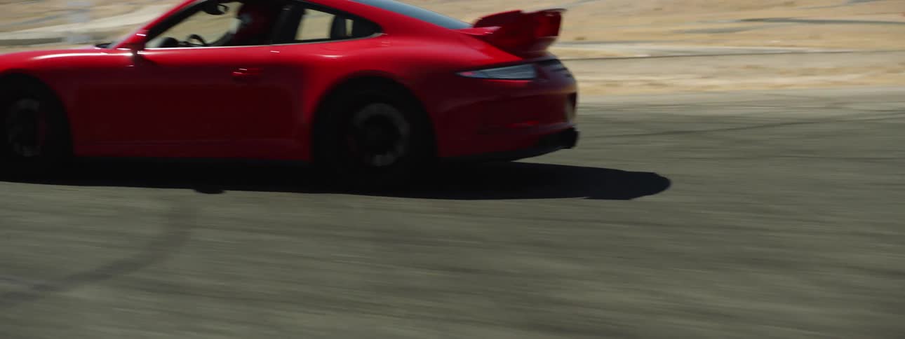 A red sports car takes off on a race track out in the desert