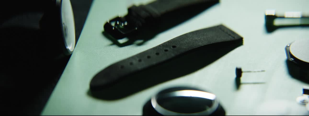 Light brightens then darkens over wrist watch parts on table