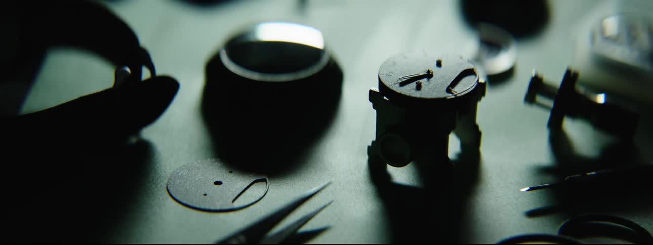 A light passes over watch and clock parts and tools on a table