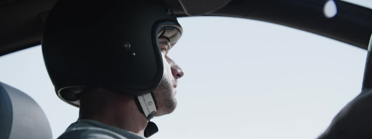 Man wearing crash helmet looks around while steering under clear sky