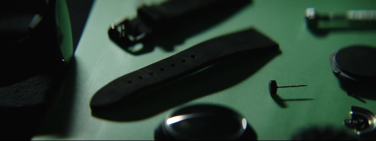 Light briefly shines across dark surface with watch band and watch face