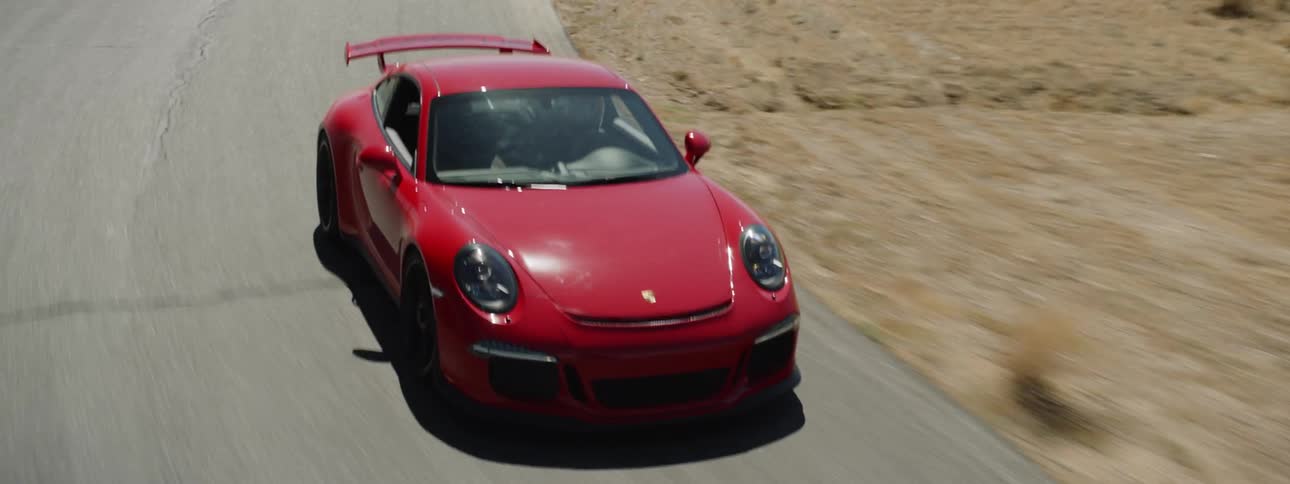 A sports car driving down a racing track in the desert