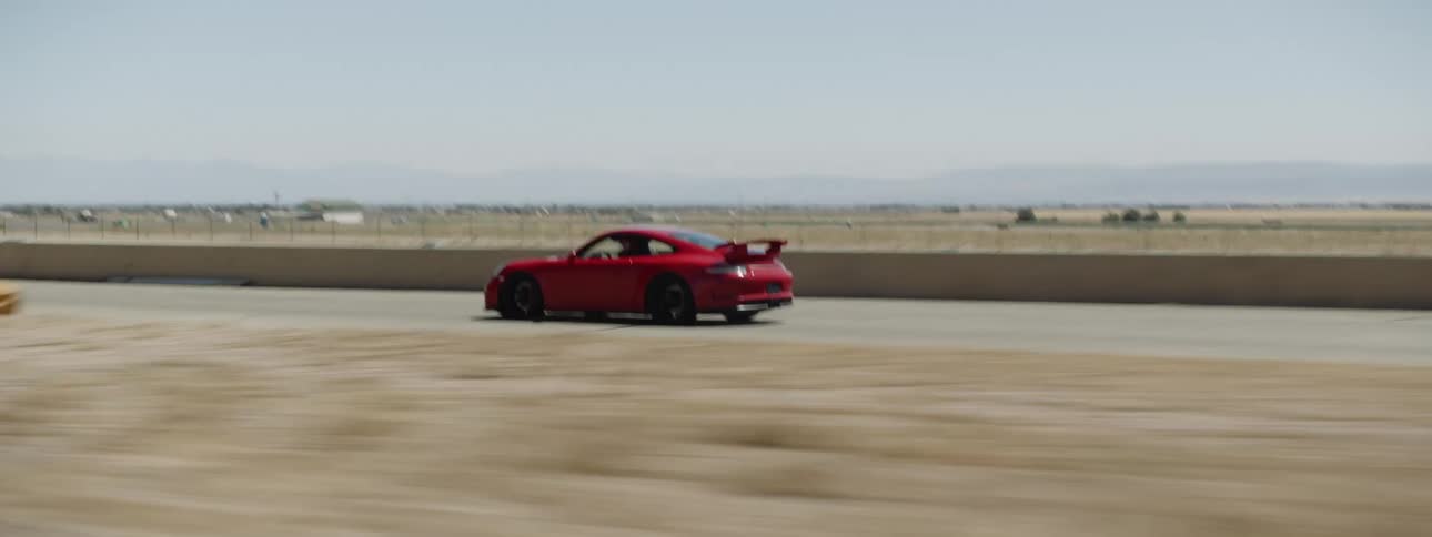 A sports car speeds around a rural deserted track