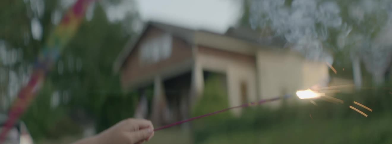 A child holds a burning sparkler in a residential area