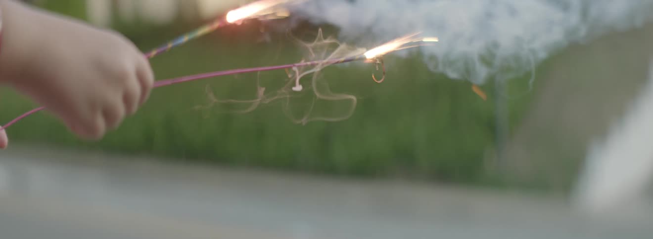 A child lights sparklers during the day