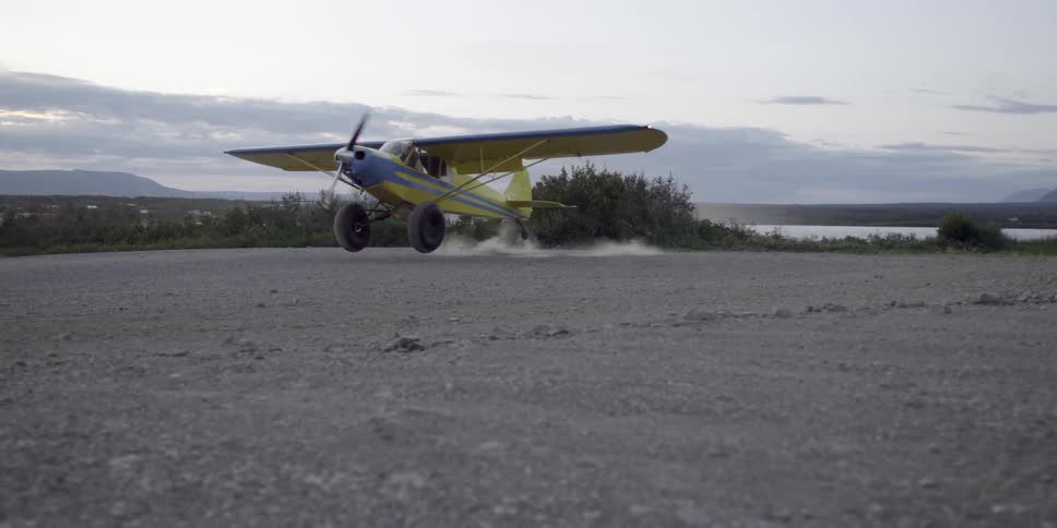 A plane is slowly landing on a runway on a cloudy day