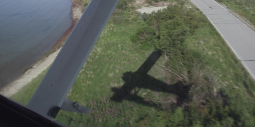 The shadow of a small plane moves over a natural landscape