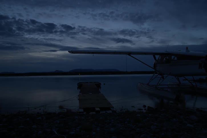 Clouds float over a mountain lake as the sky darkens