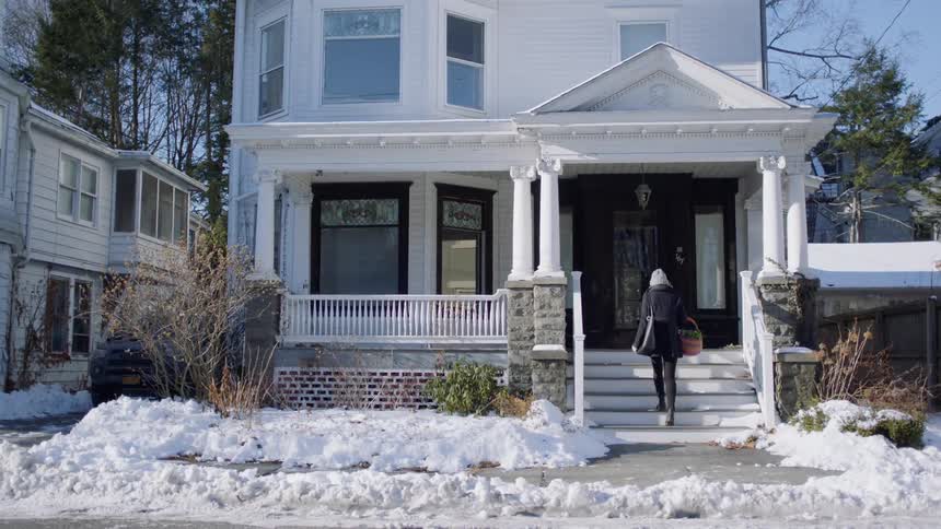 A woman arrives home and walks up the steps and unlocks her house