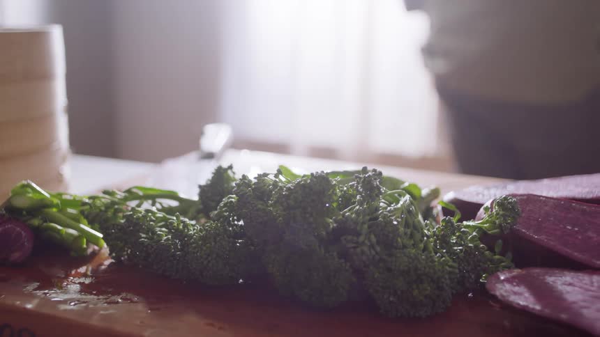 Broccoli sits on a wood cutting board in a kitchen