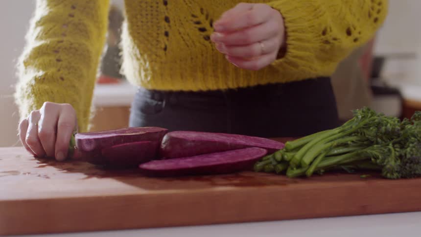 Woman puts down a knife then gathers up food clippings with her hands