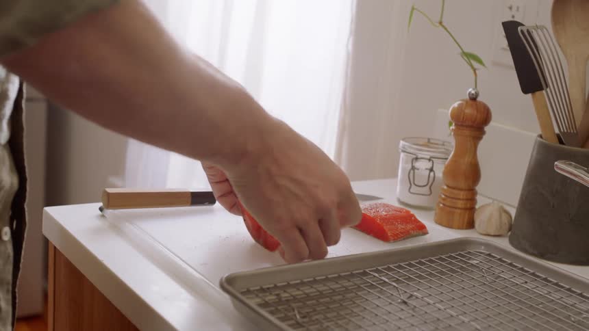 A man puts salmon in a pan to cook