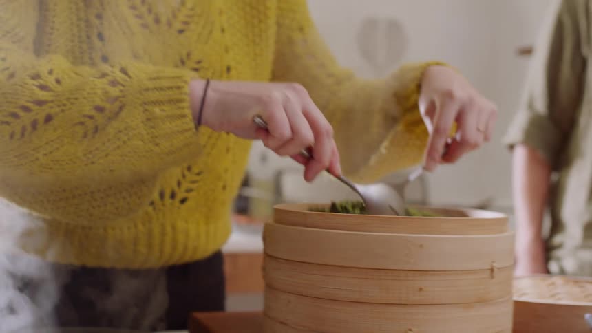 A woman takes broccoli out of a container and plates it