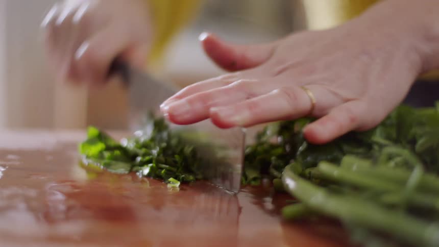 A woman is cutting vegetables in her kitchen