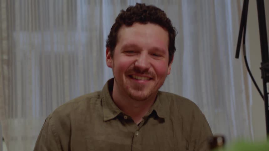 A white man sits in a room and talks to a woman